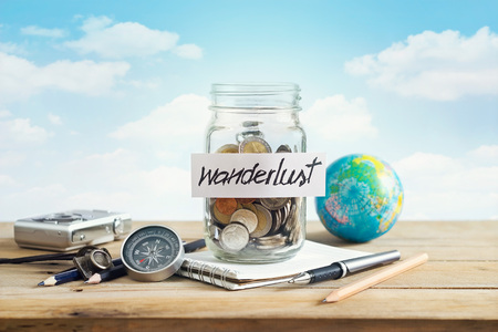 Money savings in a glass jar on blue sky background, Travel conceptの写真素材
