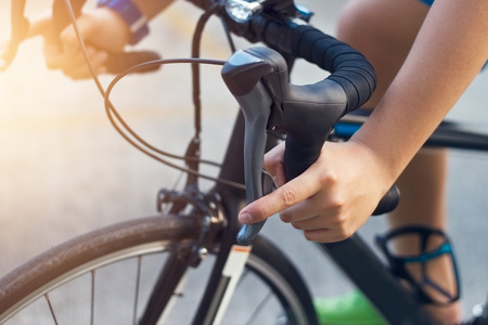 closeup hands and handlebar of a young biker on streetの写真素材