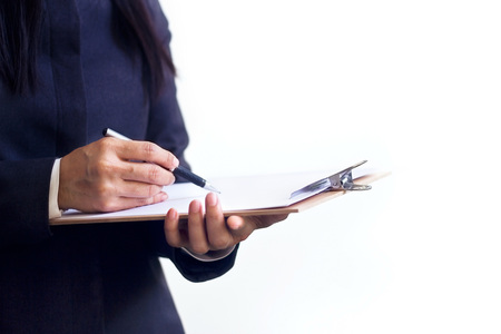Businesswoman standing writing in planner on white baclgroundの写真素材