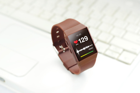 Heart rate on smartwatch screen, on keyboard of laptop backgroundの写真素材