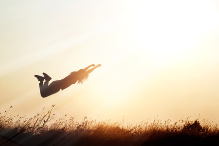 Woman flying over the meadow nature on sunset silhouette background, blank textの写真素材