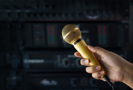 golden color microphone in woman hand in backstage of concertの写真素材