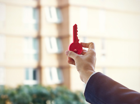 Business man holding red key on real estate background to reach goal, real estate business conceptの写真素材