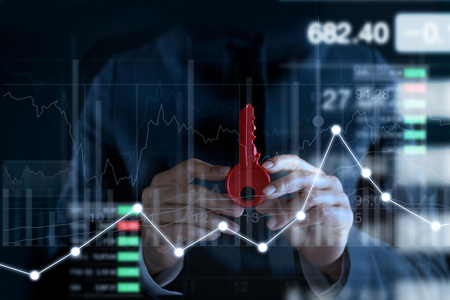 Businessman with red key for success in hands on colorful charts and diagrams stock market backgroundの写真素材