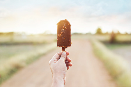 Hand of woman holding a chocolate ice cream on nature backgroundの写真素材