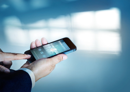 businessman holding and viewing a smartphone with stockmarket blog on screen, blank textの写真素材