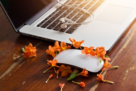 Laptop, earphone and flower on old wooden table backgroundの写真素材