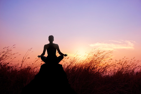 Woman yoga and meditation silhouette on nature sunset backgroundの写真素材