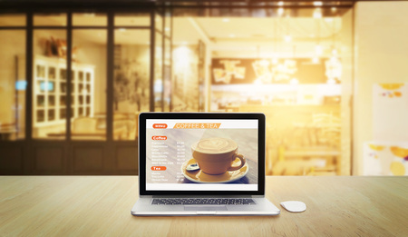 Laptop with menu coffee and tea in screen on coffee shop backgroundの写真素材