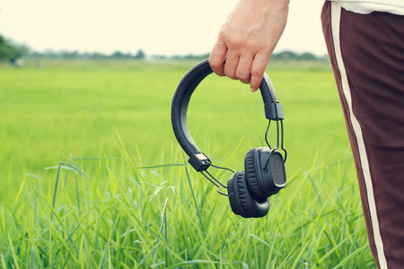 woman hand holding wireless headphone on green nature backgroundの写真素材