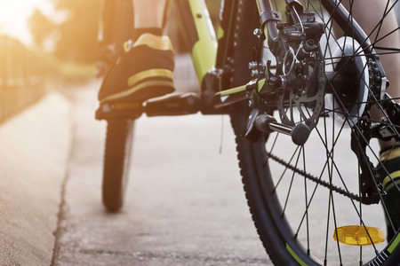Cyclist legs on bicycle on street in sunset backgroundの写真素材