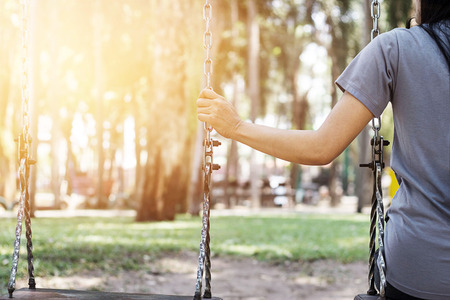 Lonely woman missing her boyfriend while swinging in the park villa in the morningの写真素材