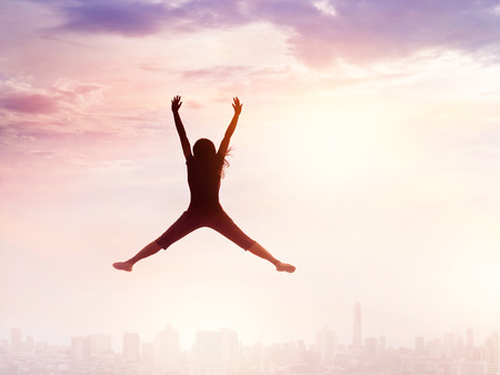 Woman enjoying jumping while chilling out on city and sky, nature backgroundの写真素材