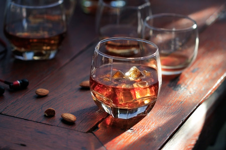 Whiskey bourbon in a glass with ice on wooden table backgroundの写真素材