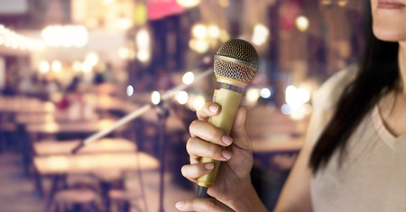 Woman holding microphone in hand on pub and restaurant backgroundの写真素材