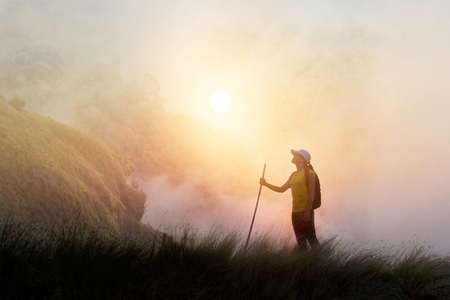 Woman backpacker hiking on mountain peak cliff in the mist.