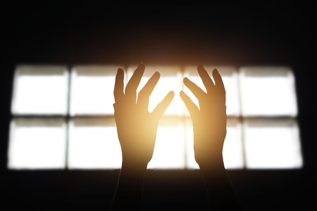 Woman hands praying for blessing from god in building on dark backgroundの写真素材