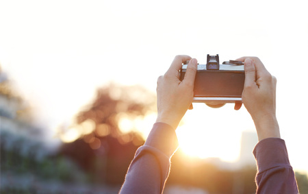 woman holding film camera taking photograph in the nature sunsetの写真素材