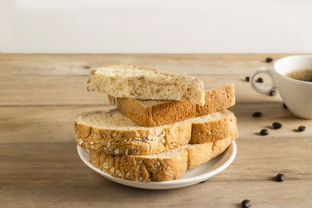Wheat bread with white sesame, coffee beans and coffee cup on wooden tableの写真素材