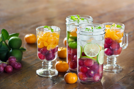 Glass refreshing detox diet drinks of mix fruits on wooden background, infusion water, healthy conceptの写真素材