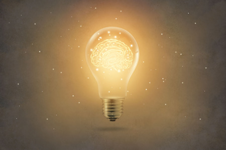 golden brain glowing inside of light bulb on paper texture backgroundの写真素材