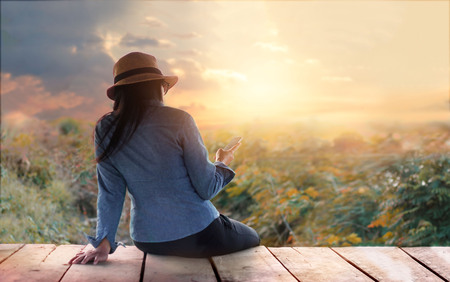 Abstract colorful, woman relaxing with smartphone in hand on outdoors in sunset rural nature backgroundの写真素材