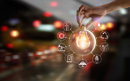 Hand holding light bulb in front of global show the world's consumtion with icons energy sources for renewable, sustainable development. Ecology and enviroment concept. Elements of this image furnished by NASA.の写真素材