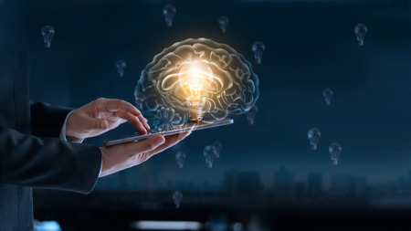 Glowing light bulb in brain over labtop of businessman among the others that not bright, it's...