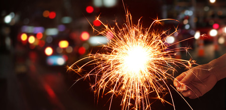 Man hand holding sparkler or firework on street night backgroundの写真素材
