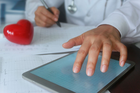 Doctor with red heart shape and annual heart health exam report, medical health care network conceptの写真素材