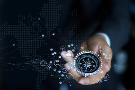 Businessman with a compass holding in hand. Define marketing direction and  search customer global networkの写真素材