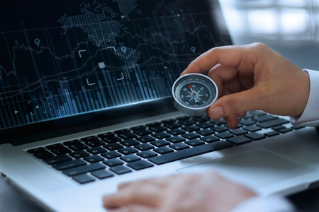 businessman holding a compass on searching screen in laptop backgroundの写真素材