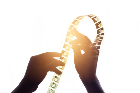 Hands of silhouette holding a film strips on lighting and white backgroundの写真素材