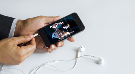 Hands insert earphone jack to smartphone with music on screen, white background, All on mobile...