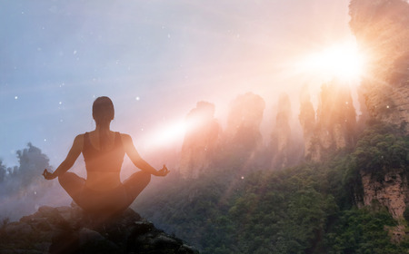 Woman meditating yoga at sunset mountains with nature. Outdoor sport exercise and relaxation conceptの写真素材