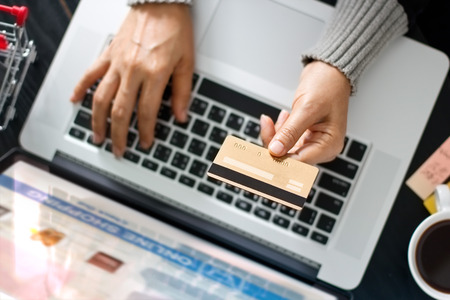 Shopping online concept. Woman holding gold credit card in hand and online shopping using on laptop...