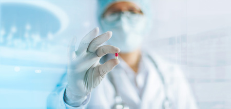 Medicine doctor holding a color capsule pill in hand with white glove in laboratory backgroundの写真素材