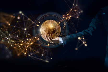 Bitcoin cryptocurrency technology and ethereum network concept. Businessman holding golden bitcoin in hand with network connection on digital dark backgroundの写真素材
