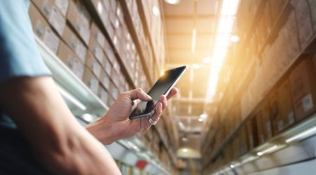 Factory worker using application on mobile smartphone to operrate automation for modern trade. Checking order in large warehouse. Import and export the shipping cargo. Business marketing and technologyの写真素材