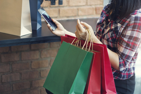 Woman with shopping bags. Using mobile smartphone for online banking in outdoor shopping mall. All on mobile screen are design up.の写真素材