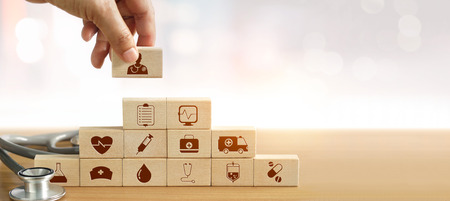 Health Insurance concept, Hand of medicine doctor holding wood block and stacking with icon healthcare medical and stethoscope on background.の写真素材