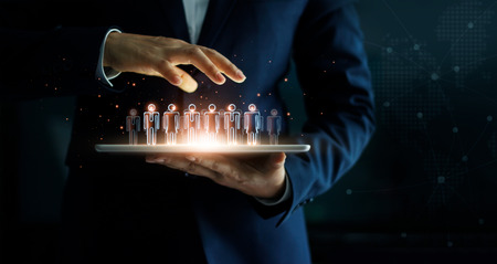 Businessman holding tablet and management group of people in his hand. Virtual icon of social network. Business technology concept.の写真素材