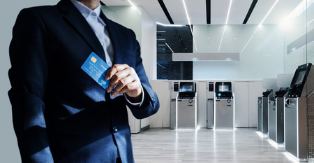 Bank manager and credit card in hand, business man standing confidently with pride in financial modern, futuristic, technology and banking network connectionの写真素材