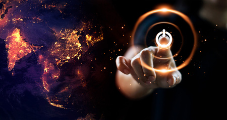 Finger pressing power button energy on earth at night background. Earth day. Environment and...