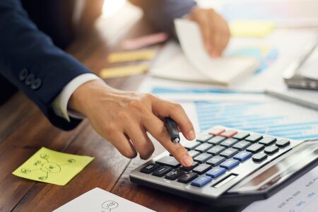 Businessman using calculator to calculate budget and analyzing sales data and growth graph, Payments, Business financing and accounting banking.の写真素材