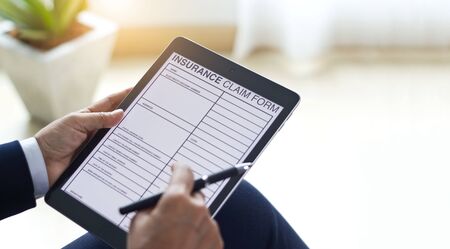 Businessman checking document and completing a insurance claim form at office work, insurance conceptの写真素材