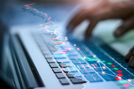 Businessman using laptop device to check market data and growth financial stock market graph on over...