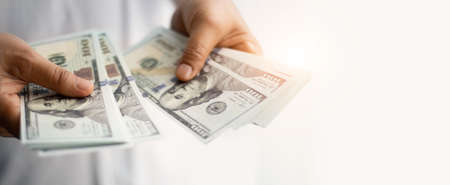 Businessman hand holding dollar bank notes, analysing growth profit from return on investment in financial trade funds and currency exchange. Managing success financial investment in economic trends.の写真素材