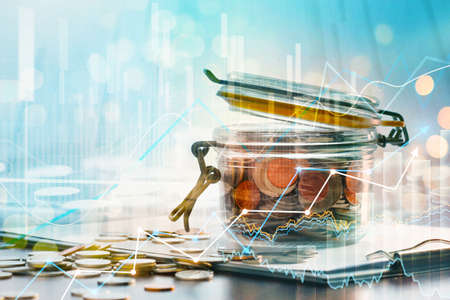 Finance and business concept. Coin in glass bottle and forex chart with stock market graph on city...