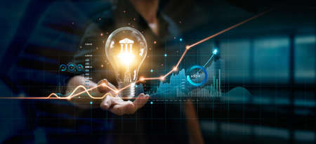 Businessman holding creative light bulb with growth graph and banking icons. Financial innovation...